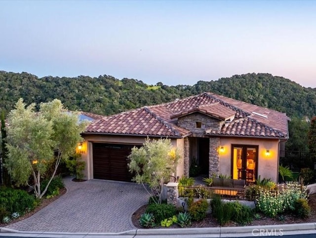 2865 Rock Wren Ln, Avila Beach, CA 93424 - mediterranean / spanish-style house with french doors, a tile roof, stone siding, a garage, and decorative driveway