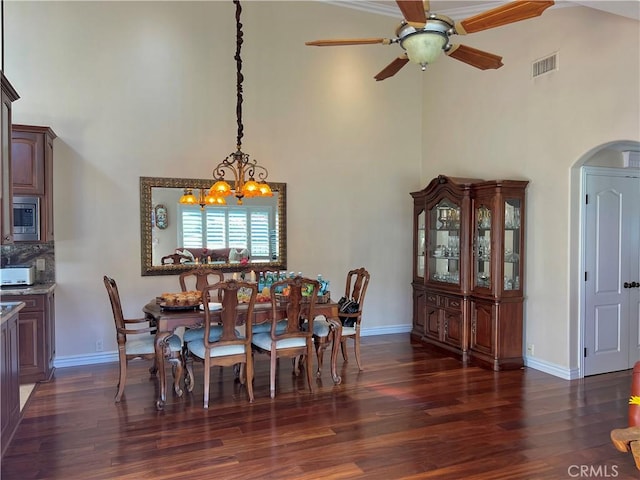 dining area with visible vents, arched walkways, dark wood finished floors, and a high ceiling