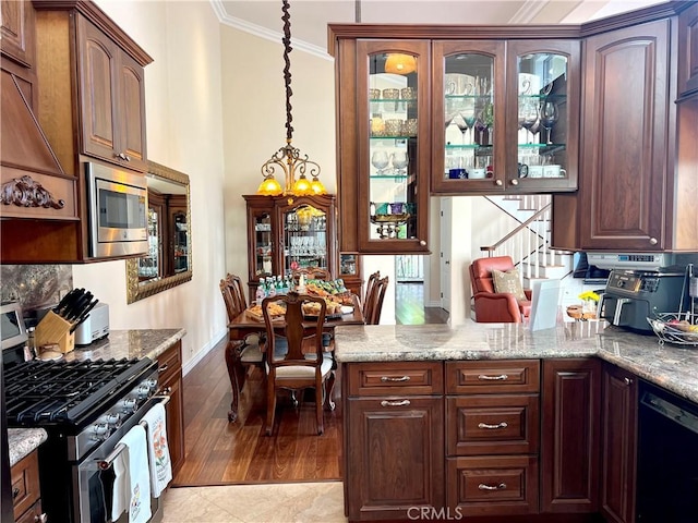 kitchen with glass insert cabinets, a chandelier, appliances with stainless steel finishes, ornamental molding, and baseboards
