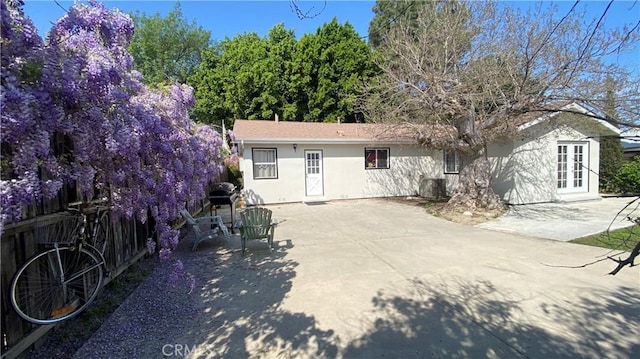 back of house featuring central air condition unit, fence, a patio, stucco siding, and french doors