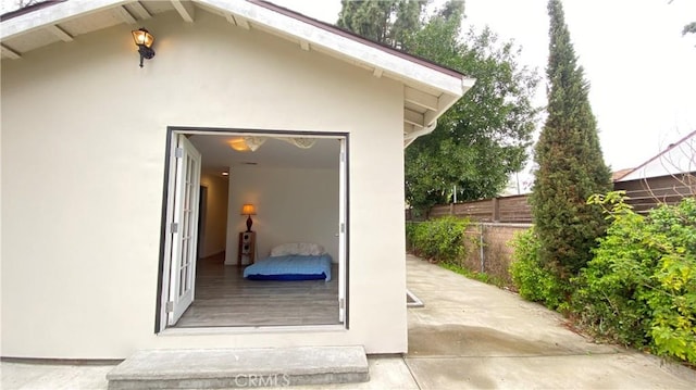 view of exterior entry with stucco siding and fence