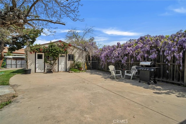 view of patio featuring grilling area, an outbuilding, and fence