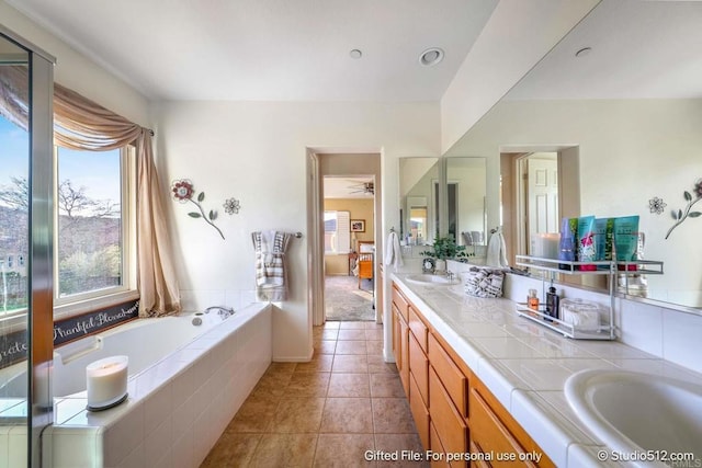 ensuite bathroom with a garden tub, a ceiling fan, tile patterned floors, a sink, and double vanity