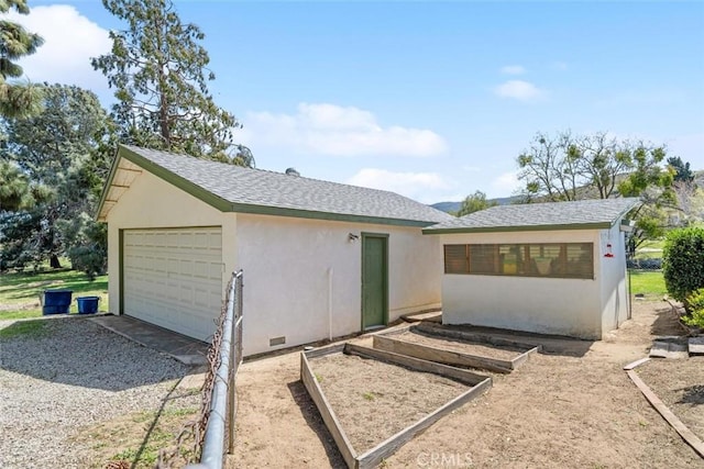 view of front of home featuring a shingled roof, a garden, and stucco siding