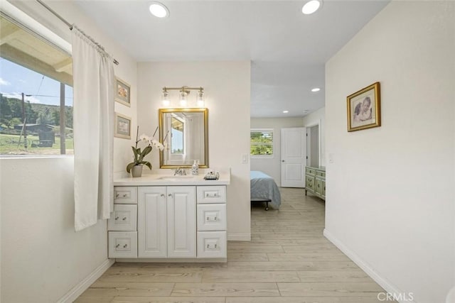 ensuite bathroom featuring vanity, recessed lighting, baseboards, wood finished floors, and ensuite bathroom