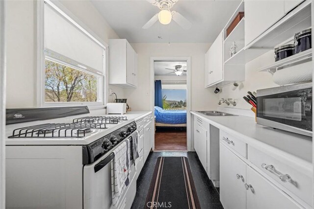 kitchen with open shelves, ceiling fan, white range with gas cooktop, stainless steel microwave, and a sink