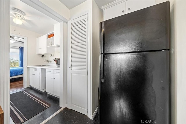kitchen featuring freestanding refrigerator, a ceiling fan, white cabinets, and light countertops