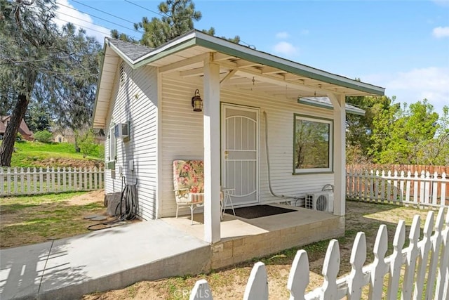 view of outdoor structure with a wall mounted air conditioner, ac unit, and fence private yard
