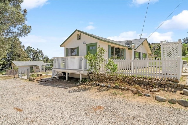 view of front of house with stucco siding, fence, and a deck