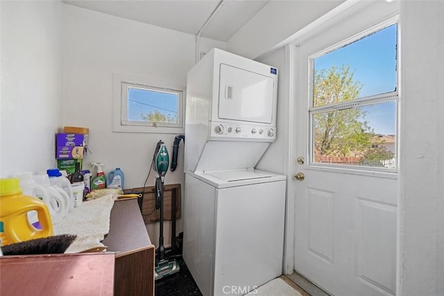 clothes washing area with laundry area, stacked washer / dryer, and a wealth of natural light