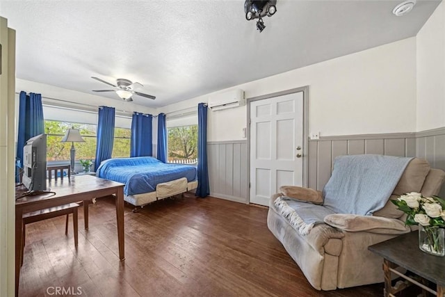 bedroom with an AC wall unit, multiple windows, hardwood / wood-style floors, and a wainscoted wall