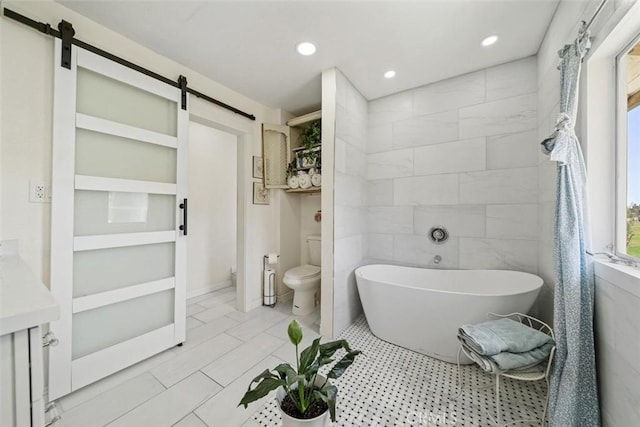 bathroom with toilet, a freestanding bath, recessed lighting, and vanity