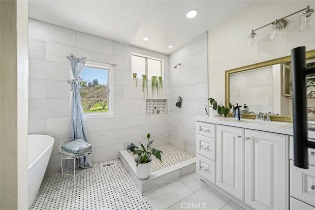 full bathroom featuring vanity, a freestanding tub, tile walls, visible vents, and tiled shower