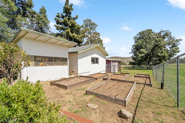 back of house with a lawn, fence, a garden, and stucco siding