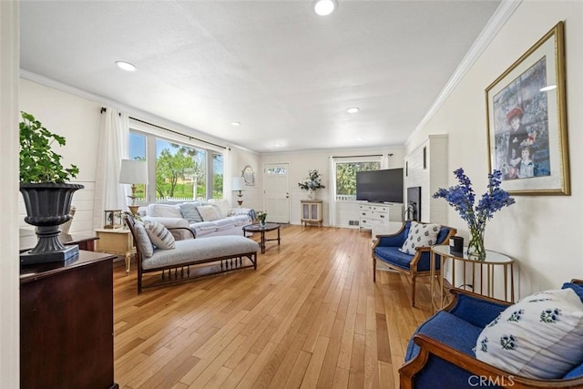 living area with crown molding, recessed lighting, and light wood finished floors