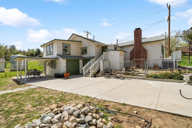 rear view of property featuring a gate, a carport, stairway, fence, and a patio