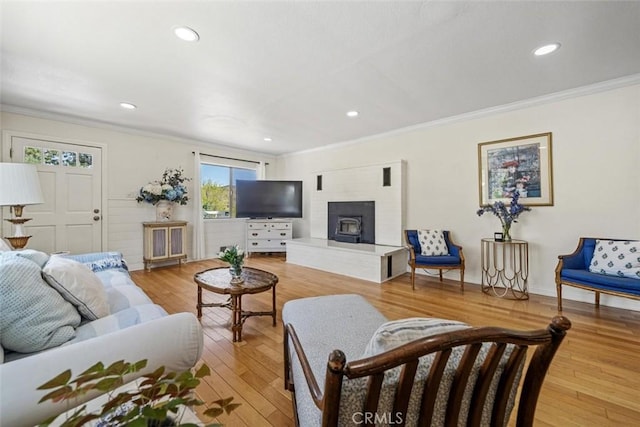 living room featuring recessed lighting, ornamental molding, and light wood-type flooring