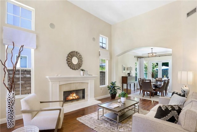 living room featuring arched walkways, a wealth of natural light, visible vents, and wood finished floors