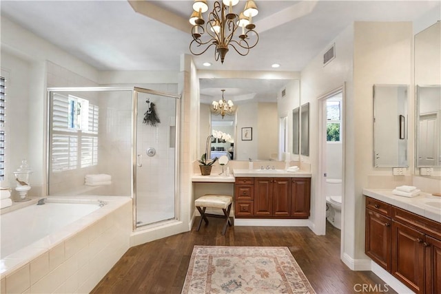 bathroom featuring a garden tub, wood finished floors, an inviting chandelier, and a stall shower