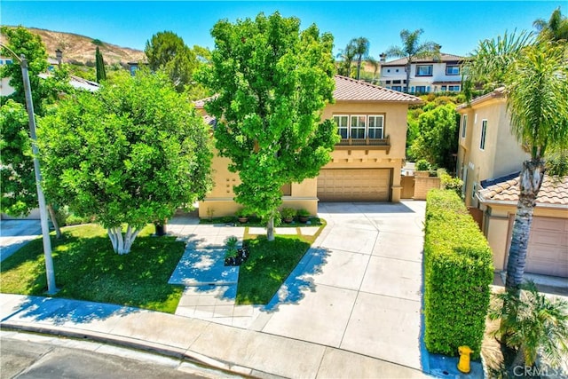 view of front of house with stucco siding, an attached garage, a tiled roof, and concrete driveway