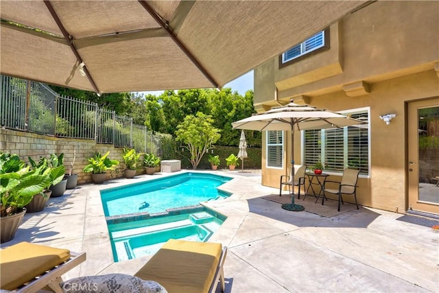 view of swimming pool featuring fence, a pool with connected hot tub, and a patio area