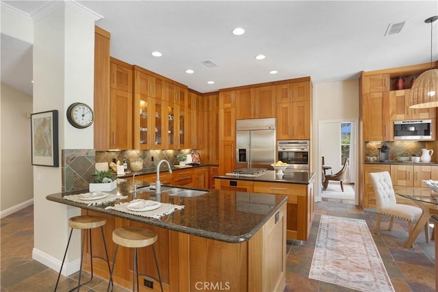 kitchen featuring stone tile floors, a sink, backsplash, appliances with stainless steel finishes, and visible vents