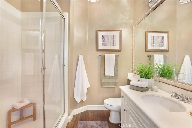 bathroom with wood finished floors, a stall shower, toilet, and vanity