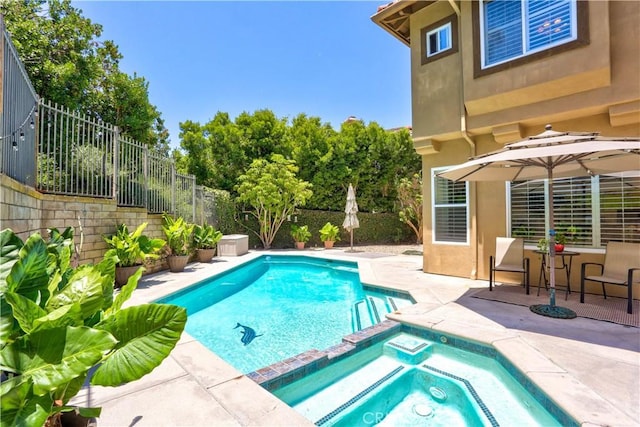 view of pool with a pool with connected hot tub, fence, and a patio area