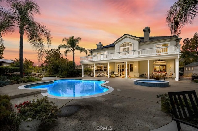 outdoor pool with an in ground hot tub, ceiling fan, a patio area, and outdoor lounge area