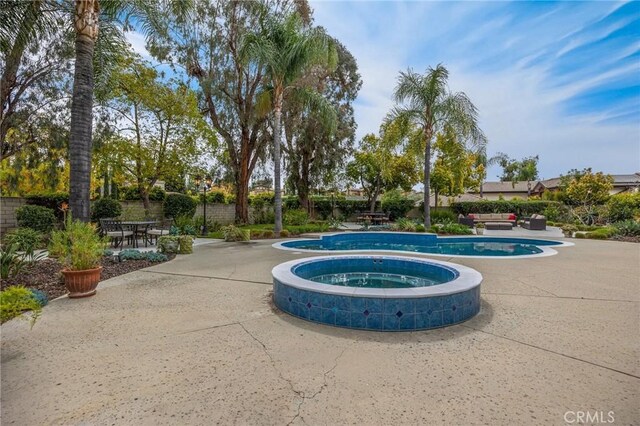view of swimming pool featuring a fenced in pool, an in ground hot tub, and a patio area