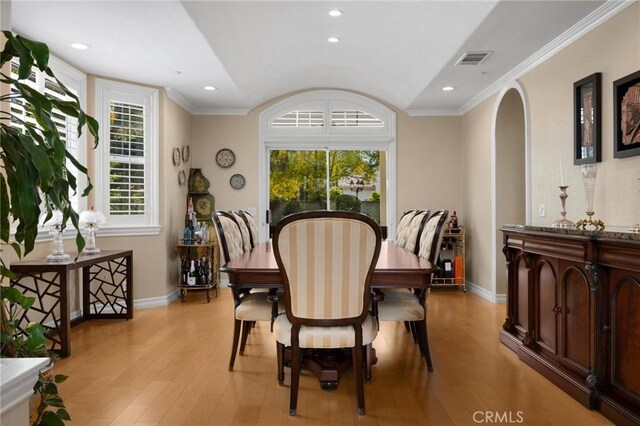 dining room with arched walkways, baseboards, visible vents, and light wood-type flooring