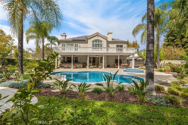 rear view of house with a patio, an in ground hot tub, stucco siding, and an outdoor pool
