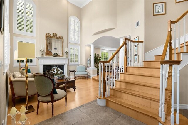interior space featuring a fireplace, stairs, baseboards, a towering ceiling, and visible vents