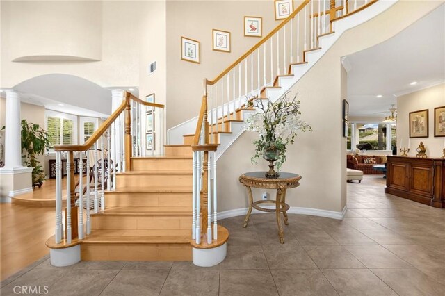stairway featuring a healthy amount of sunlight, baseboards, ornate columns, and a towering ceiling