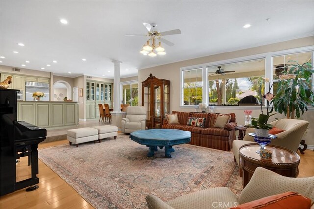 living room featuring a ceiling fan, recessed lighting, ornate columns, and light wood-type flooring