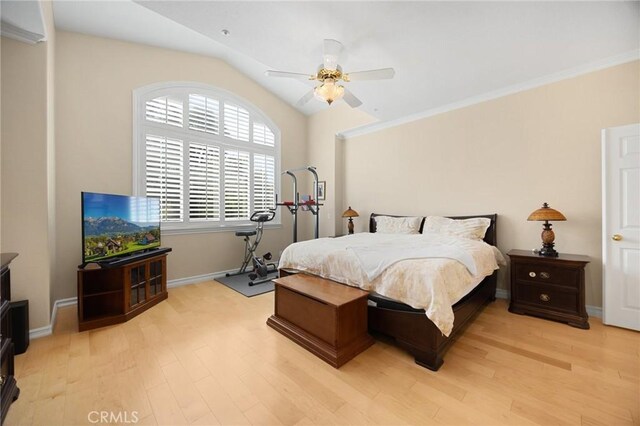 bedroom with crown molding, ceiling fan, light wood-style floors, baseboards, and vaulted ceiling