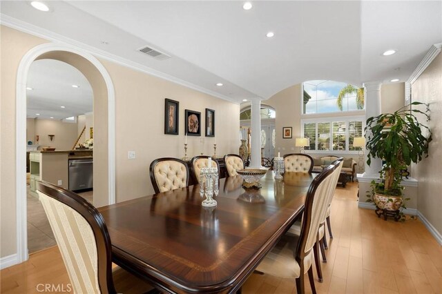 dining space featuring visible vents, decorative columns, recessed lighting, arched walkways, and light wood-style flooring