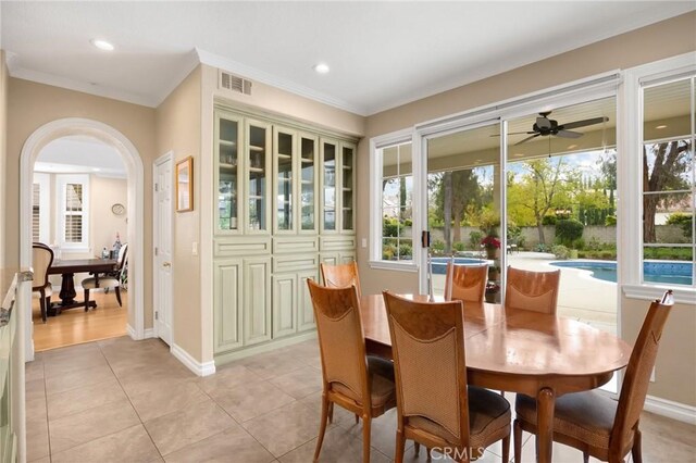 dining area featuring crown molding, arched walkways, ceiling fan, and visible vents