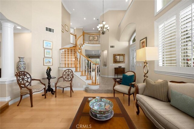 living room featuring decorative columns, a high ceiling, visible vents, and baseboards