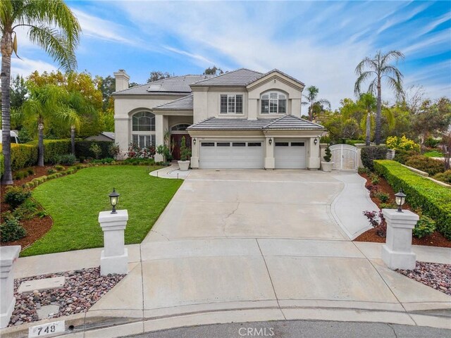 view of front of property featuring an attached garage, stucco siding, a front yard, roof mounted solar panels, and driveway
