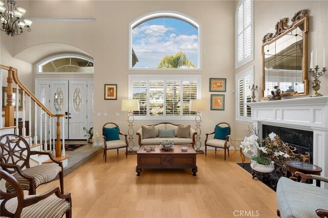 living area featuring an inviting chandelier, a towering ceiling, and wood finished floors