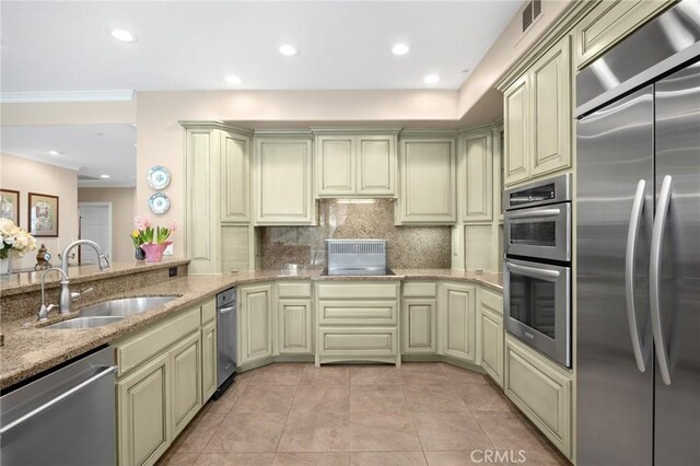 kitchen with light stone countertops, appliances with stainless steel finishes, a sink, backsplash, and visible vents
