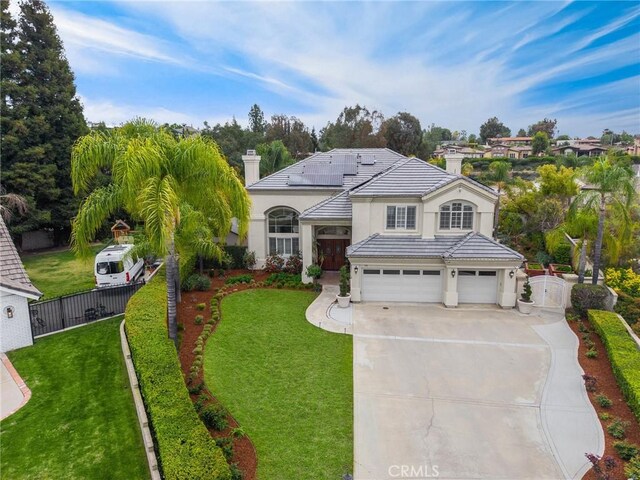 traditional-style home featuring fence, a front lawn, stucco siding, solar panels, and driveway