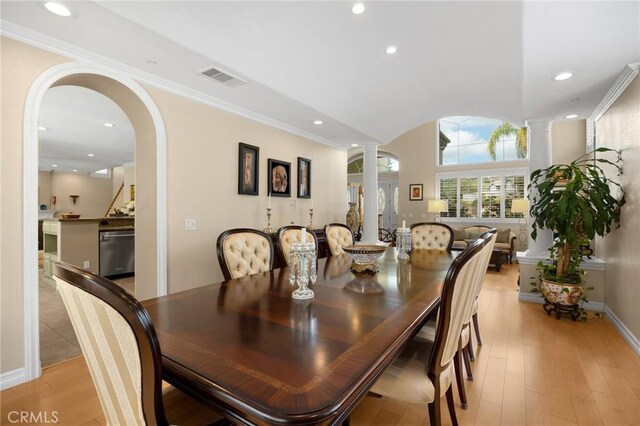 dining area featuring decorative columns, visible vents, arched walkways, recessed lighting, and light wood-style flooring
