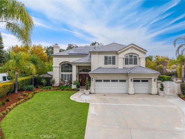 traditional-style house featuring an attached garage, a front lawn, stucco siding, a tiled roof, and driveway