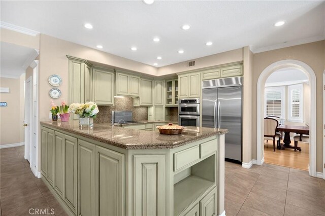 kitchen with light stone counters, ornamental molding, recessed lighting, and stainless steel appliances