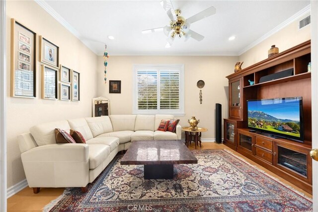 living area featuring crown molding, a ceiling fan, baseboards, and wood finished floors