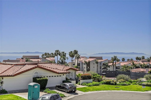 view of front of property with a residential view, a mountain view, an attached garage, a tiled roof, and fence
