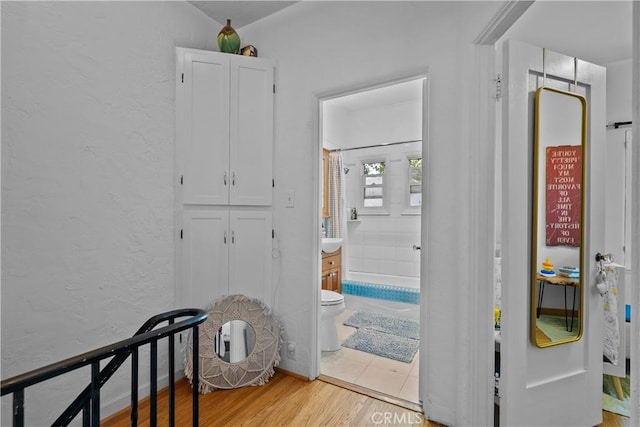 hallway featuring a textured wall and light wood finished floors