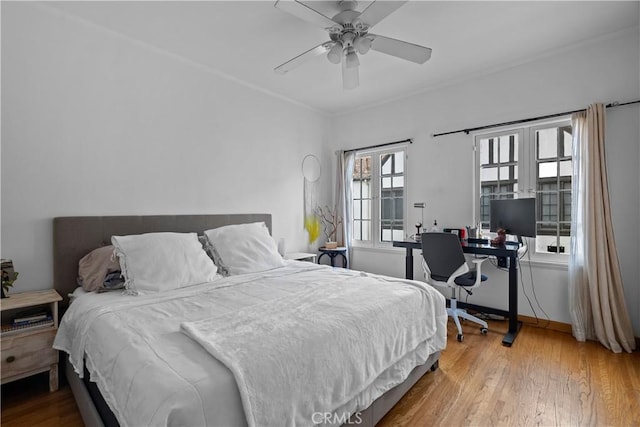 bedroom with baseboards, ceiling fan, crown molding, and wood-type flooring